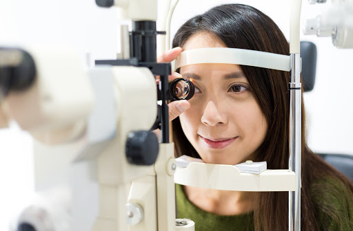 Young happy woman undergoing eye exam by her optometrist